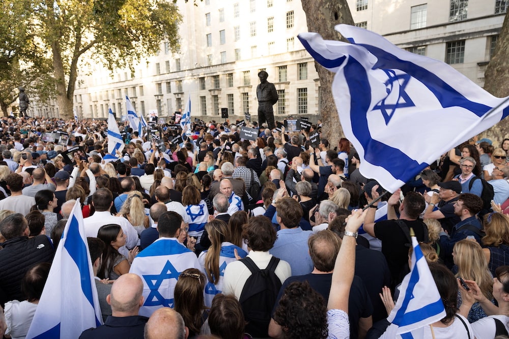 An image of a crowd of pro-Israel demonstrators protesting near Downing Street in London. Many wave flags of Israel.