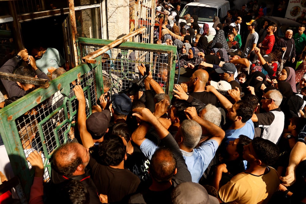 Palestinians queue as they wait to buy bread from a bakery, amid shortages of food supplies and fuel as the conflict between Israel and Palestinian Islamist group Hamas continues, in Khan Younis.