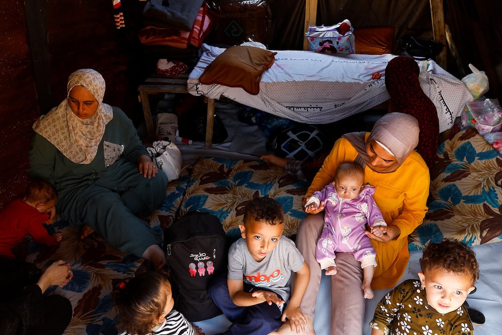 Women sit with children as displaced Palestinians, who fled their homes due to Israeli strikes, take shelter at Nasser hospital, in Khan Younis.