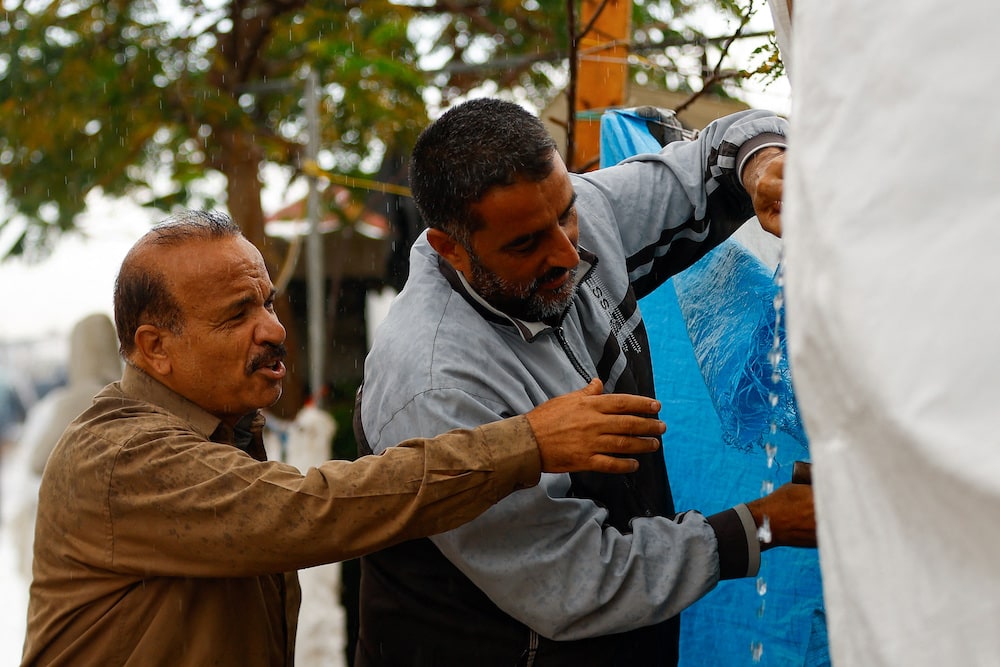 Displaced Palestinians work to fix a tent under the rain as people shelter in a tent camp, amid the conflict between Israel and Palestinian Islamist group Hamas, in Khan Younis.