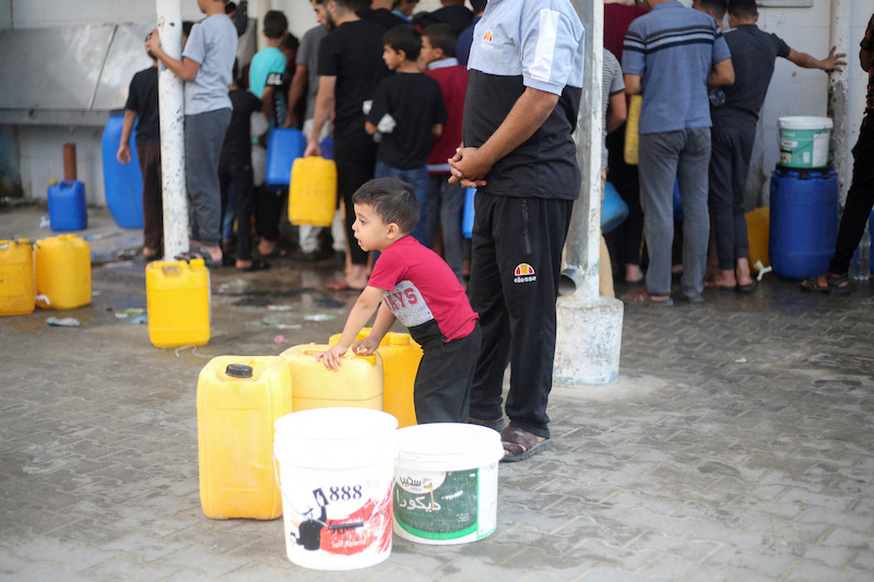 A boy stands among plastic containers in a crowd of Palestinians collecting water, amid the ongoing Israeli-Palestinian conflict in Khan Younis in the southern Gaza Strip.