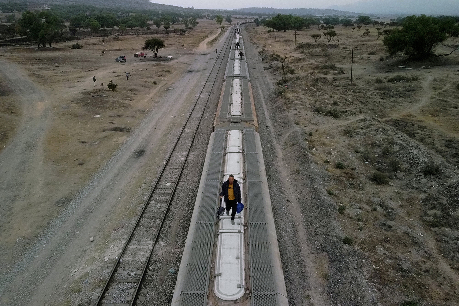 Migrants, mostly from Venezuela, walk on top of railroad cars as they get ready to continue their journey to the U.S. border in the site known as El Basurero, a stretch of land next to a trash dump and the railroad, in Huehuetoca, State of Mexico, Mexico, April 26, 2023. REUTERS/Gustavo Graf