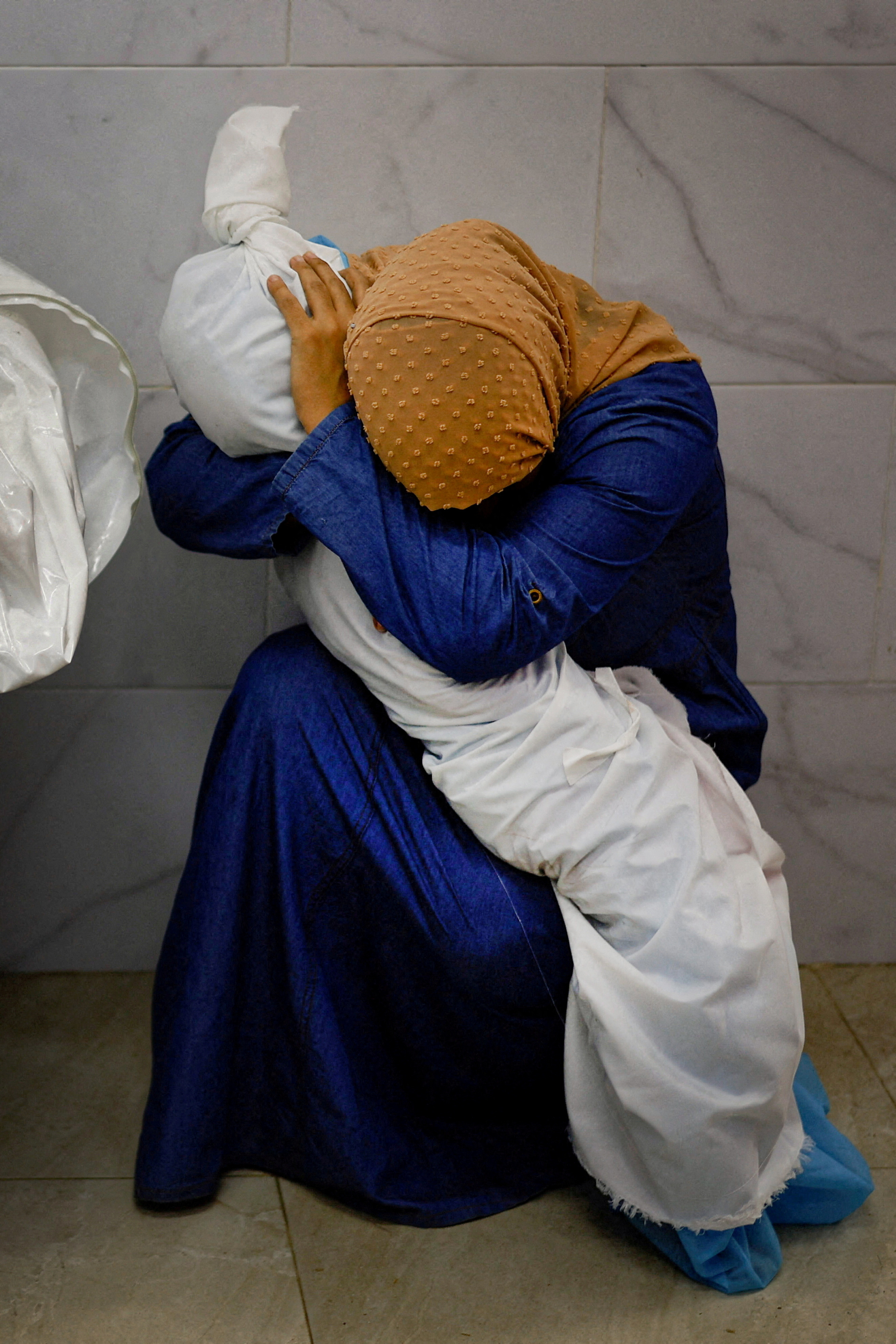 Palestinian woman Inas Abu Maamar, 36, embraces the body of her 5-year-old niece Saly, who was killed in an Israeli strike, at Nasser hospital in Khan Younis in the southern Gaza Strip, October 17, 2023. REUTERS/Mohammed Salem