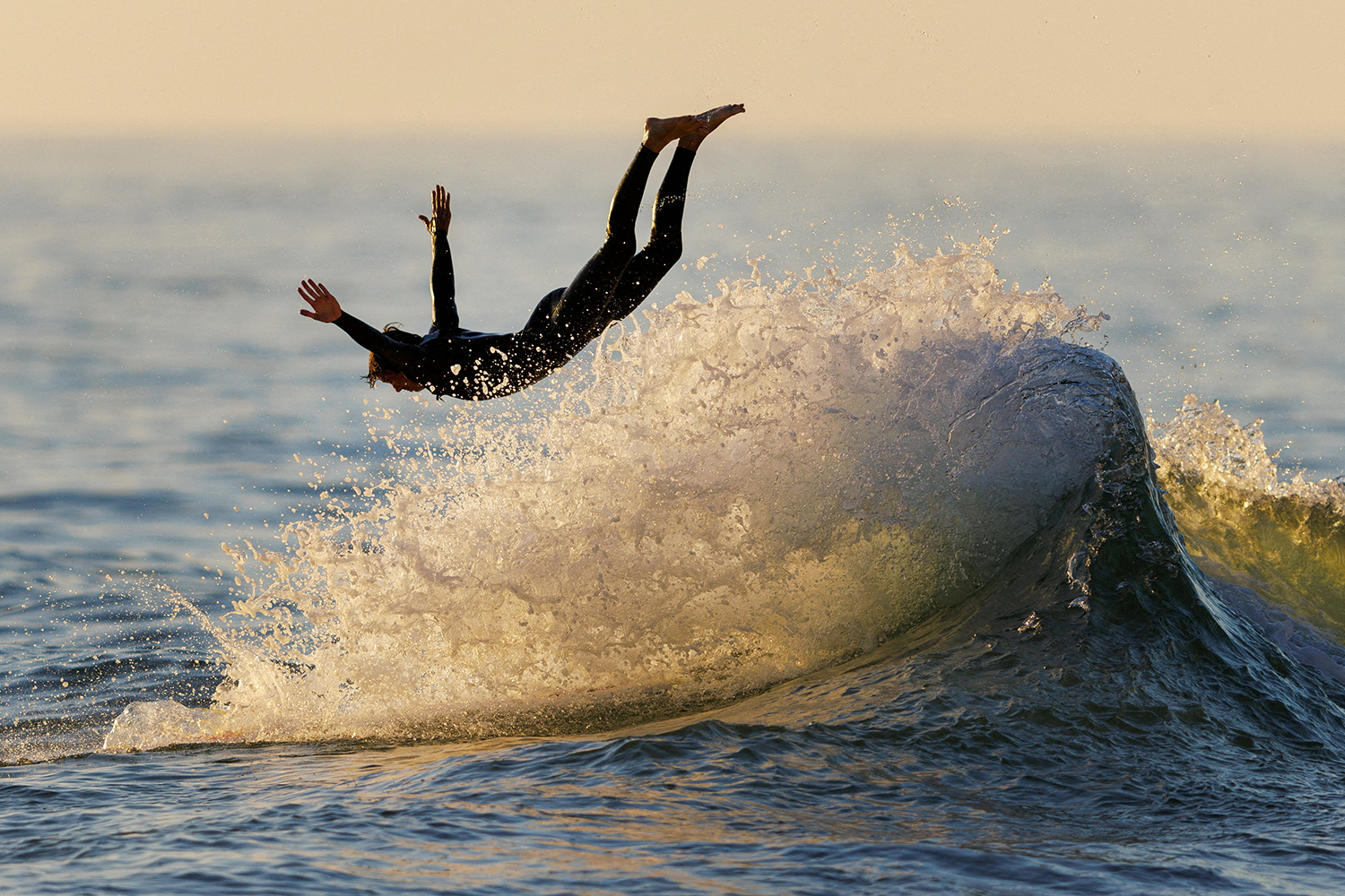 A surfer dives off his board at sunset in Encinitas, California, U.S., August 28, 2023. REUTERS/Mike Blake