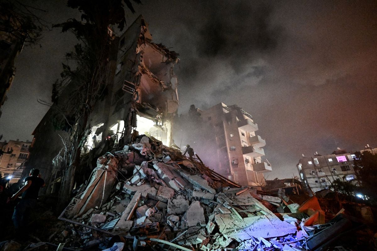 Several people working to clear debris and rubble from a damaged apartment building.
