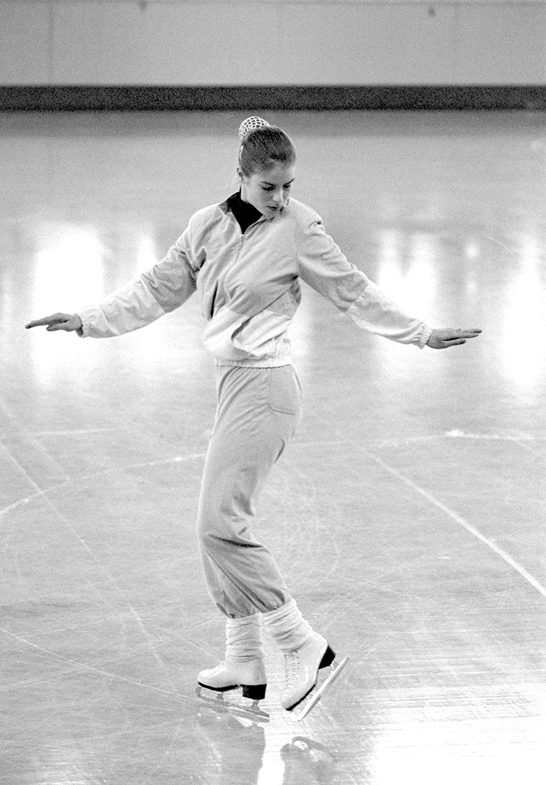 A black-and-white image of a figure skater moving backwards to create a compulsory figure.