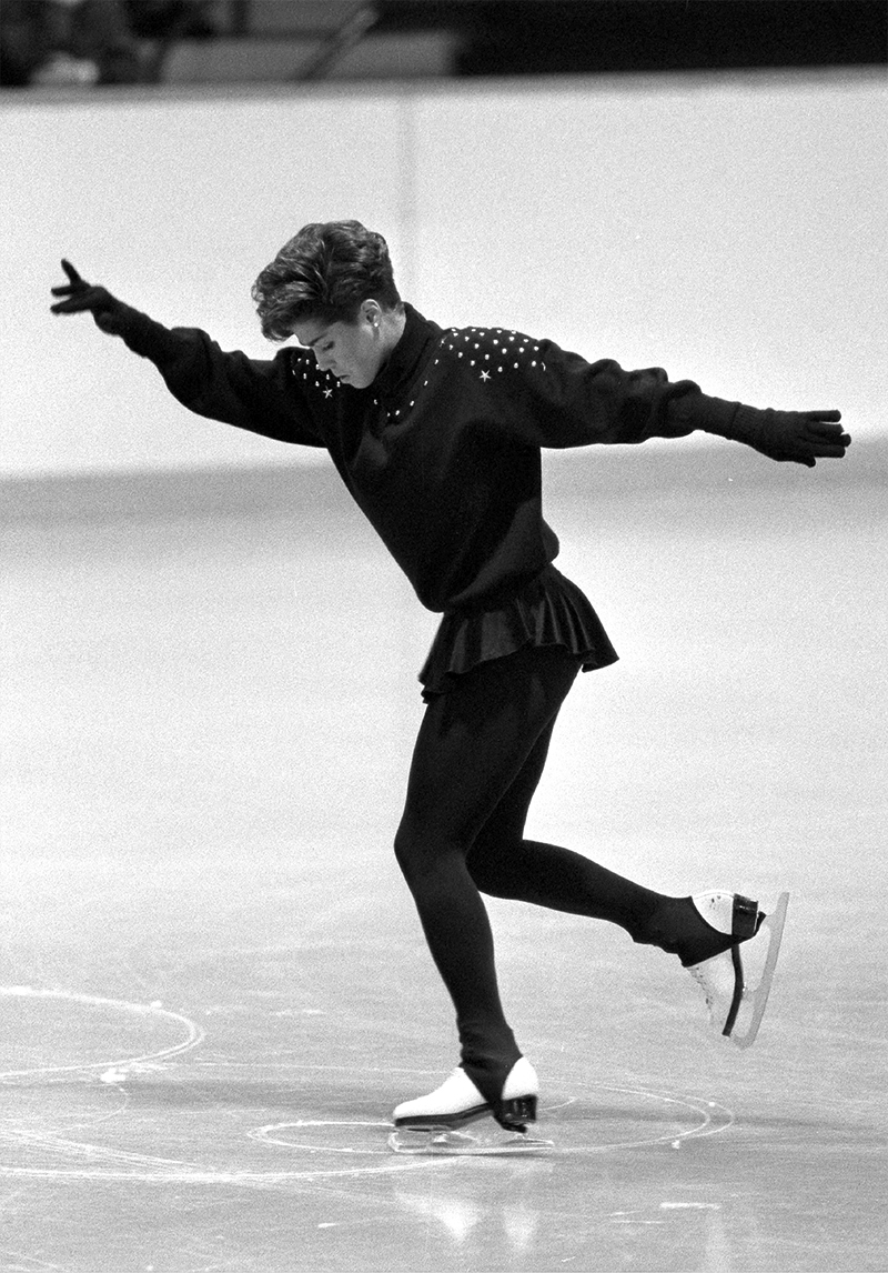 A black-and-white image of a figure skater moving forward while creating a compulsory figure.